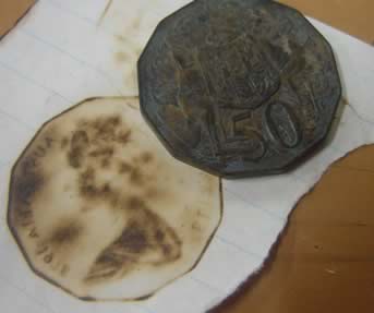 A burnt coin and the print it made on a piece of paper.
